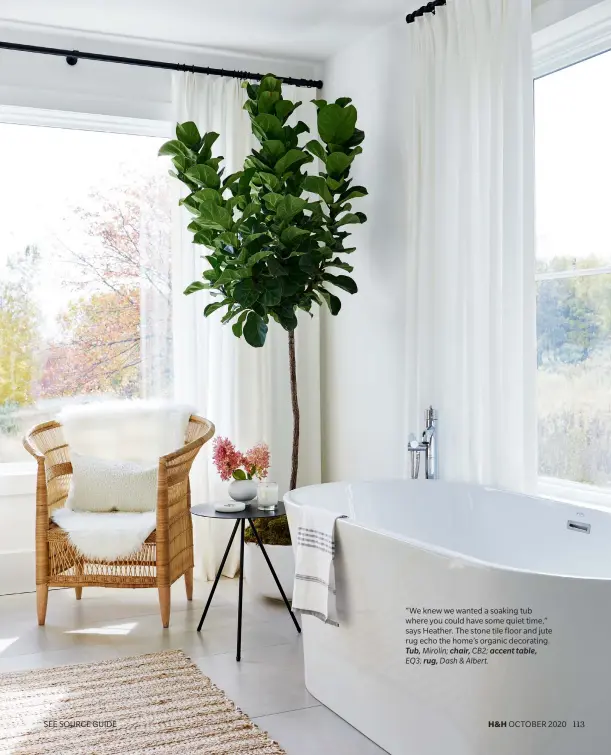  ??  ?? “We knew we wanted a soaking tub where you could have some quiet time,” says Heather. The stone tile floor and jute rug echo the home’s organic decorating. Tub, Mirolin; chair, CB2; accent table, EQ3; rug, Dash & Albert.