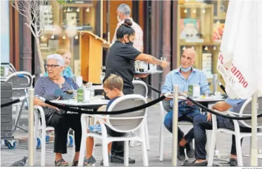  ?? JAVIER ALBIÑANA ?? Una camarera sirve a varios clientes en una terraza de Málaga capital.