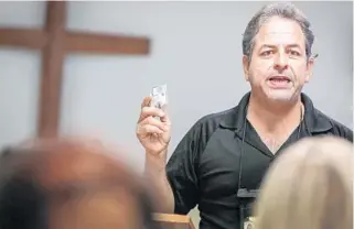  ?? PHOTOS BY JACOB LANGSTON / ORLANDO SENTINEL ?? Retired firefighte­r Luis Garcia holds up a pack of Narcan that he was giving out during a class at Saint Philip Lutheran Church in Mount Dora.