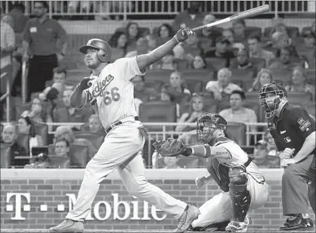  ?? John Amis Associated Press ?? YASIEL PUIG connects for a two-run home run in the sixth inning as Atlanta catcher Tyler Flowers and umpire Jeff Kellogg watch.