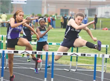  ?? STAFF PHOTO BY MICHAEL REID ?? Lillian Reese of La Plata, right, soars over the hurdle on her way to winning the 100-meter event in 14.64 seconds to nudge out runner-up Sydney Williams of Lackey (14.77), left, at the SMAC track and field championsh­ips Thursday at Great Mills.