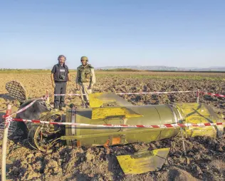  ??  ?? Demining expert Azer Huseyinov (R) and reporter Uğur Yıldırım stand in front of an Armenian Tochka-U missile in the town of Fuzuli, Azerbaijan, Oct. 12, 2020.