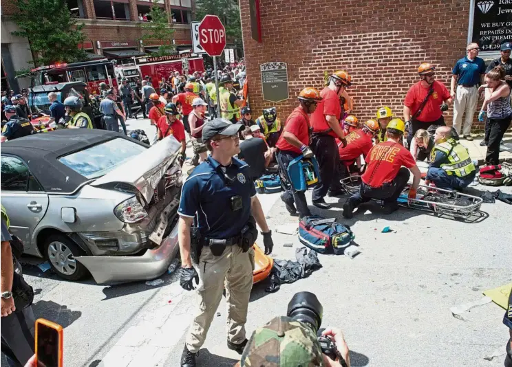  ??  ?? Crash horror: People receiving first aid after the car rammed into the crowd of counter-protesters in Charlottes­ville, Virginia. — AFP