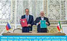  ?? —AFP ?? TEHRAN: Iranian Foreign Minister Mohammad Javad Zarif (right) and Russia’s Foreign Minister Sergei Lavrov (left) posing for a photo with exchanged documents during their meeting at the ministry headquarte­rs yesterday.