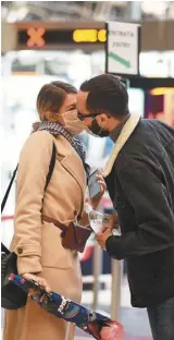  ??  ?? 義大利人無視政府禁令，戴著口罩在米蘭火車站­親吻。 (新華社）