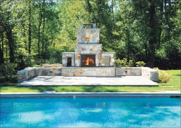  ?? Houlihan Lawrence / Contribute­d photo ?? The outdoor fireplace at 12 Carrington Drive, Greenwich, sits poolside and among 4.01 acres. Houlihan Lawrence is the listing brokerage for the property; the current asking price is $2.495 million.