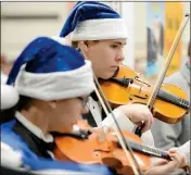  ??  ?? Violinists Rebecca Rey (left) and her brother Juston Rey play a Christmas song at the Yuma Orchestra Associatio­n booth.