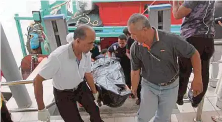  ?? PIC BY SHARUL HAFIZ ZAM ?? The body of a Thai fisherman, who drowned after his boat capsized, is carried to shore in Kuala Kedah yesterday.