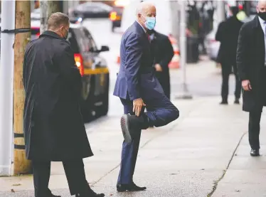  ?? ANDREW HARNIK/THE ASSOCIATED PRESS ?? President-elect Joe Biden touches a boot on the foot he recently injured as he arrives on Friday at The Queen theatre in Wilmington, Del. Biden plans to ask Americans to wear masks during his first 100 days in the White House.