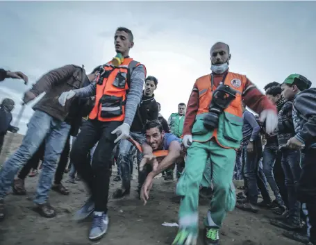  ?? EPA ?? Palestinia­n medics carry a wounded youth away from clashes near the border between Israel and the Gaza Strip on Friday