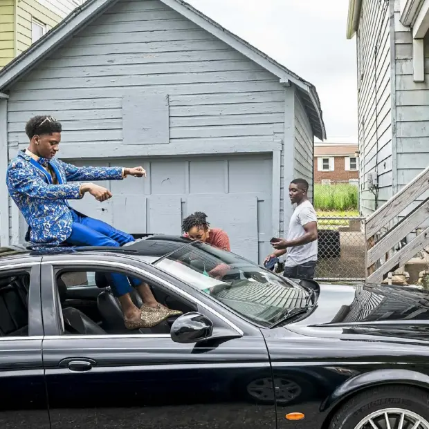  ??  ?? Before attending his high school graduation, Rasaun Brown dances while sitting on the sunroof of a car owned by his uncle, David Hutchinson, of Beltzhoove­r, center oover, center. Rasaun’s aunt, Candace Dixon, of the Hill District, photograph­s his shoes while his father, Shaun Jackson, of Manchester, records the scene.