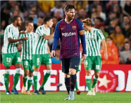 ?? — Reuters ?? No magic return: Barcelona’s Lionel Messi looking dejected as Real Betis players celebrate after the La Liga match at the Nou Camp on Sunday.