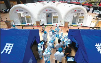  ?? Photo: cnsphoto ?? Lab staff prepare before entering Beijing’s first membrane “Fire Eye” lab for nucleic acid tests, which entered operations on Tuesday. Nine 3.5-meter tall membrane cabins, with 14 automated nucleic acid extraction machines, can collect samples of 30,000 people a day.
