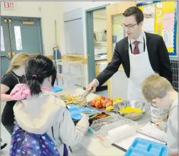  ?? NICK PROCAYLO/ PNG ?? Colin Scarlett, senior vice- president of Colliers Internatio­nal, serves breakfast to students at Hastings elementary school on Wednesday.