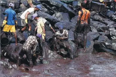  ?? ARUN SANKAR/ AGENCE FRANCE-PRESSE ?? Volunteers try to clean up oil that has washed ashore in Chennai, southern India, on Saturday, after an oil tanker and an LPG tanker collided off Kamarajar Port in Ennore. Hundreds of students and fishermen were working to clean up the oil spill that...
