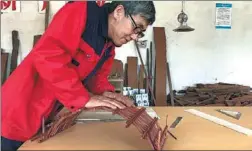  ?? ZHANG WENJING / XINHUA ?? Sun Gang tests the strength of a model wooden-arch bridge he made by putting his weight on it in his workshop in Dingxi, Gansu province.