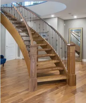  ??  ?? Engineered, walnut hardwoods sweep the basement level where a curved walnut staircase with wrought iron spindles flows elegantly to its base.