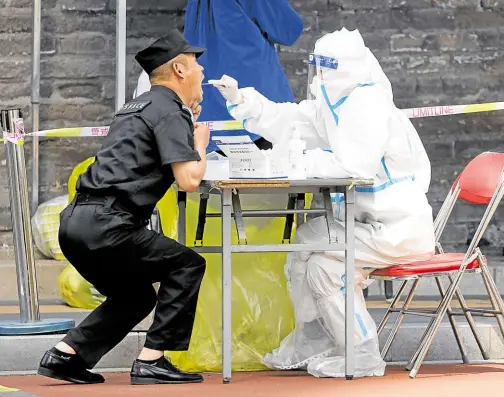  ?? ?? OFTEN ENOUGH A medical worker in a protective suit collects a swab sample from a man at a makeshift nucleic acid testing site amid the COVID-19 outbreak in Beijing on May 11. WHO guidelines have never recommende­d mass screening of asymptomat­ic individual­s—as is currently happening in China—because of the costs involved and the lack of data on its effectiven­ess.