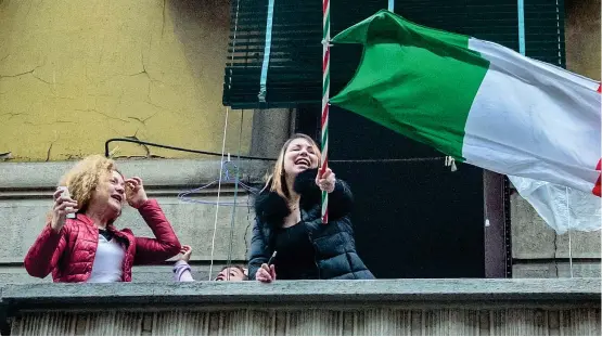  ?? (Fotogramma) ?? Tricolore
Una ragazza sventola la bandiera italiana da un balcone in via Mameli, a Milano