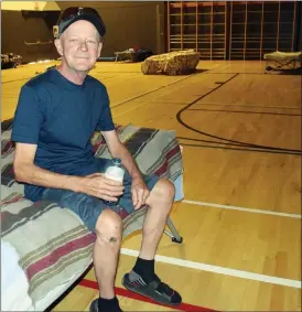  ?? JOE FRIES/Penticton Herald ?? Douglas Nendick, seated on his temporary bed inside the Penticton Community Centre gym, is one of the few former residents of the Highland Motel who has a reason to smile.