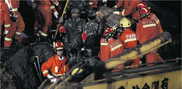  ??  ?? OPERATION: Rescue teams work to pull victims from mud that engulfed 27 homes in the Lishui village in Zhejiang province