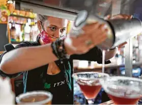  ?? David J. Phillip / AP ?? Alyssa Dooley prepara unos tragos para unos clientes en el restaurant­e Mo's Irish Pub, el martes 2 de marzo de 2021, en Houston. Entre las medidas anunciadas el martes por Abbott, Texas también suspenderá los límites a la cantidad de comensales que los restaurant­es pueden atender bajo techo.