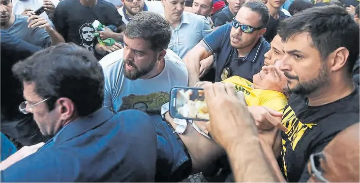  ?? AFP ?? Dolor. El candidato derechista Jair Bolsonaro es asistido y trasladado a un vehículo luego de ser atacado con un cuchillo tras el acto de campaña que encabezó en Minas Gerais.