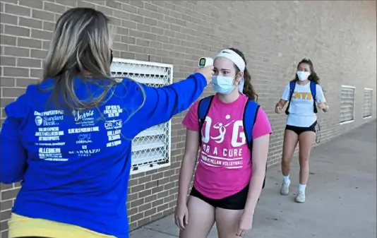  ?? Darrell Sapp/Post-Gazette ?? Canon-McMillan girls volleyball coach Sheila Mitchell checks junior Leah Peters’ temperatur­e before the team’s first practice since the onset of the COVID-19 pandemic. Mitchell said coaches wear masks at all times. Players do not have to wear them while practicing.