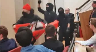  ??  ?? Invasion: Masked protesters barge into the controvers­ial university debate