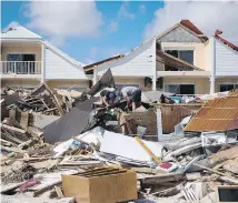  ?? MARTIN BUREAU / AFP / GETTY IMAGES ?? Hurricane Irma left a trail of destructio­n through many small Caribbean islands before attacking Florida on Sunday. Two men, left, look for belongings in the rubble of their restaurant Sunday on a beach in Orient Bay on the French island of St. Martin....