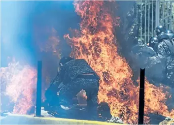  ?? JUAN BARRETO/GETTY IMAGES ?? Police officers react after an explosion during a protest of elections for a constituti­onal assembly in Caracas, Venezuela, on Sunday. Deadly violence erupted around the controvers­ial vote, with a candidate to the all-powerful body shot dead and troops...