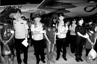  ?? HAN YUQING / XINHUA ?? Police officers escort telefraud suspects at Nanjing Lukou Internatio­nal Airport in Jiangsu province last Tuesday. A total of 63 suspects were brought back from Cambodia and accused of defrauding people on the Chinese mainland by posing as law...
