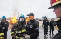  ??  ?? North Las Vegas firefighte­r Darcy Loewen instructs recruit Devon Turner during a car fire exercise at the Las Vegas Fire Department training facilities.