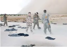  ?? — AFP ?? Fighters from the Syrian Democratic Forces (SDF) walk along a road dotted with IS group-mandated black veils shed by women after they crossed into SDF territory near Tishreen Farms, on the northern outskirts of Raqa.