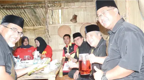  ??  ?? Abang Johari (third right) showing and enjoying the local delicacy ‘Kelupis Limbang’ as Awang Tengah (second right), Hasbi (left) and other guests smile.