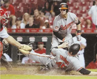  ?? AP PHOTO ?? FLYIN’ WITH TRUMBO: Baltimore’s Mark Trumbo (45) scores the go-ahead run past Cincinnati catcher Stuart Turner in the 10th inning of the Orioles’ 2-1 win last night.