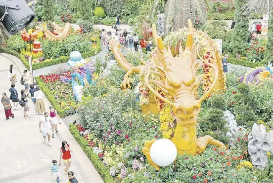  ?? ROSLAN RAHMAN/AGENCE FRANCE-PRESSE ?? VISITORS walk past a dragon-themed sculpture displayed to celebrate the upcoming Lunar New Year inside the flower dome at Garden by the Bay in Singapore on 1 February 2024.