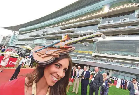  ?? Atiq ur Rehman/Gulf News ?? A model poses with a hat showing a guitar during the Dubai World Cup race day at the Meydan Racecourse yesterday. Despite early morning drizzle, it failed to dampen the spirits of the race lovers.