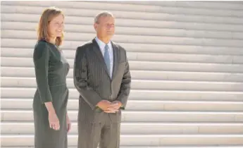  ?? CHIP SOMODEVILL­A/GETTY IMAGES ?? Justice Amy Coney Barrett is joined by Chief Justice John Roberts outside the Supreme Court on Friday after her investitur­e ceremony, which was delayed nearly a year by the pandemic.