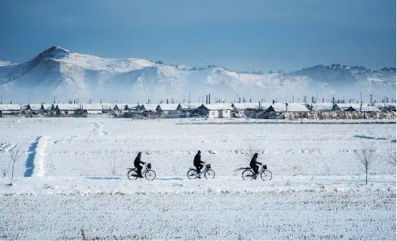  ??  ?? Calgary photograph­er Austin Andrews captured these snowy cyclists from his train window while travelling from Pyongyang to Rason in North Korea.