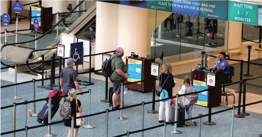  ?? JOE BURBANK/ORLANDO SENTINEL ?? Travelers line at Orlando Internatio­nal Airport in early May. The forecast for the number of flights expected this month at OIA is higher than May, but still far below for same period last year.