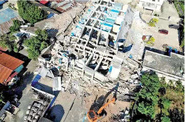  ??  ?? An earth remover works to clear debris from the collapsed Roa Roa hotel where up to 60 people are feared to be buried. — AFP photo