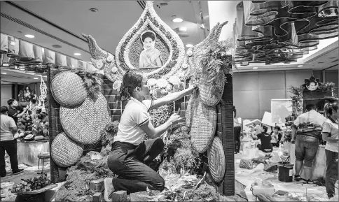  ??  ?? A Thai woman puts together the background to a decoration that will include different vegetable and fruit decoration­s.