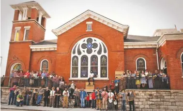  ?? PHOTO BY GARY HAMILTON ?? Fans and performers pose in front of Lindsey Street Hall on M.L. King Boulevard for a group photo during the Great Southern Old-Time Fiddlers’ Convention in 2014.