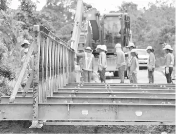  ??  ?? JKR and CMS personnel building the bailey bridge.