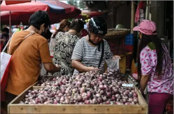  ?? ?? Customers shopping for onions at a market in Manila.