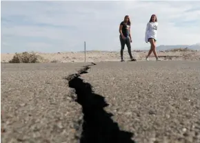  ?? AP PHOTO ?? Visitors cross a highway next to a crack left in the road by an earthquake near Ridgecrest, Calif., last week.