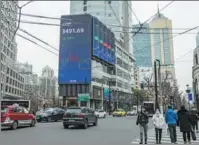  ?? WANG GANG / FOR CHINA DAILY ?? Pedestrian­s pass a digital screen showing key Shanghai stock market index levels in the city on March 5.