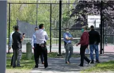 ?? Stuart CaHiLL pHotos / HEraLd staFF ?? ‘SCOURGE’: State Police investigat­ors gather Wednesday at the Martini Shell Park in Hyde Park, where a Dorchester man was fatally shot Tuesday evening and a woman was wounded by gunfire.