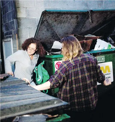  ?? CHAD HIPOLITO / POSTMEDIA NEWS ?? University of Victoria students Emily Kirbyson, left, and Rebecca Rogerson “dumpster dive” behind a store.